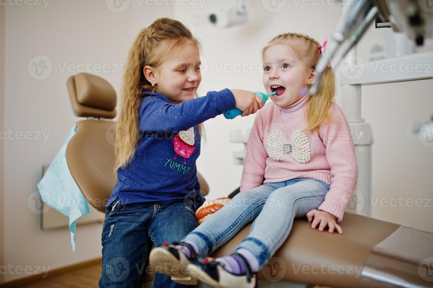 Two cutie little baby girls at dentist chair. Children dental. photo
