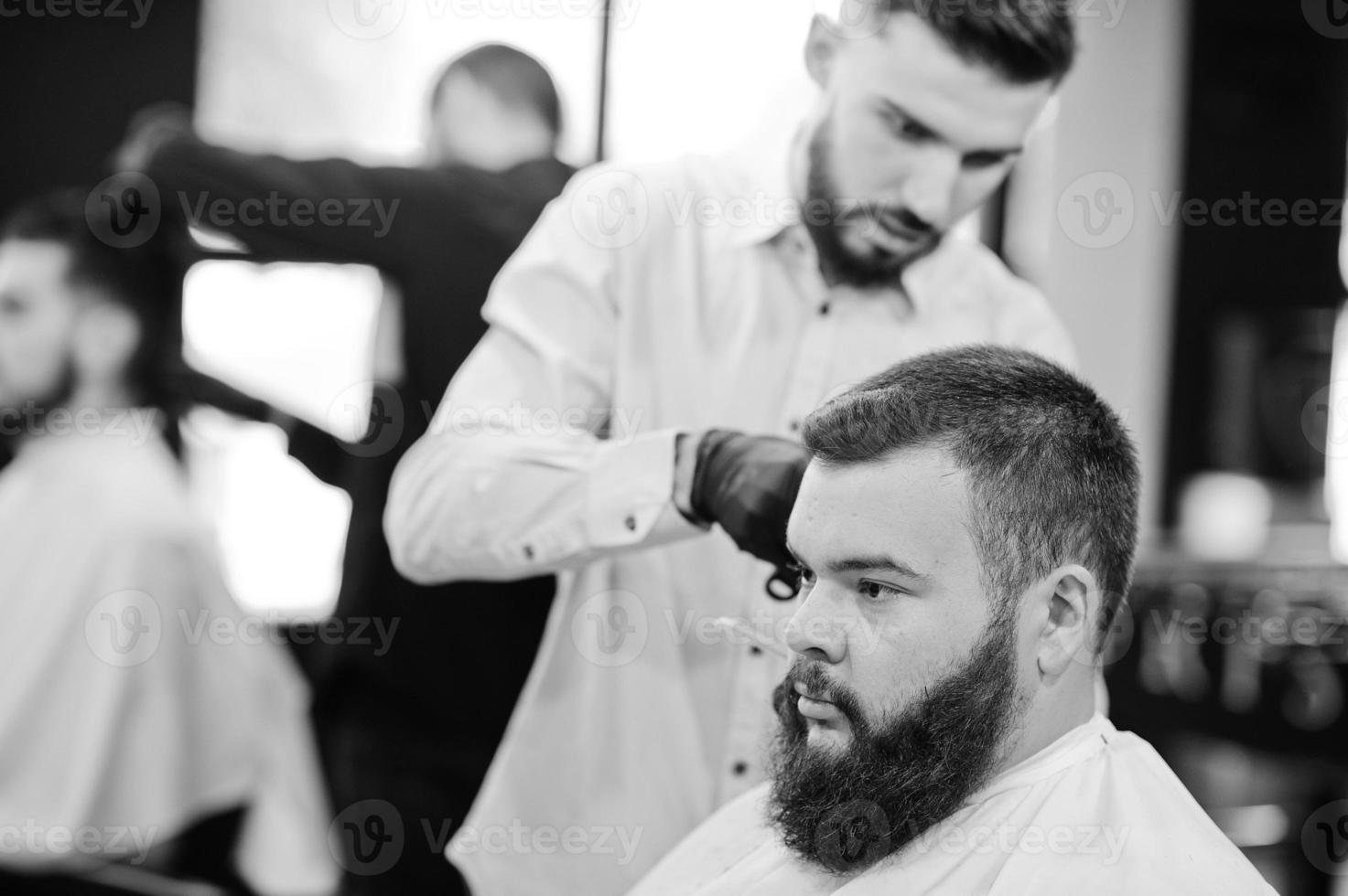 apuesto hombre barbudo en la barbería, peluquero en el trabajo. foto