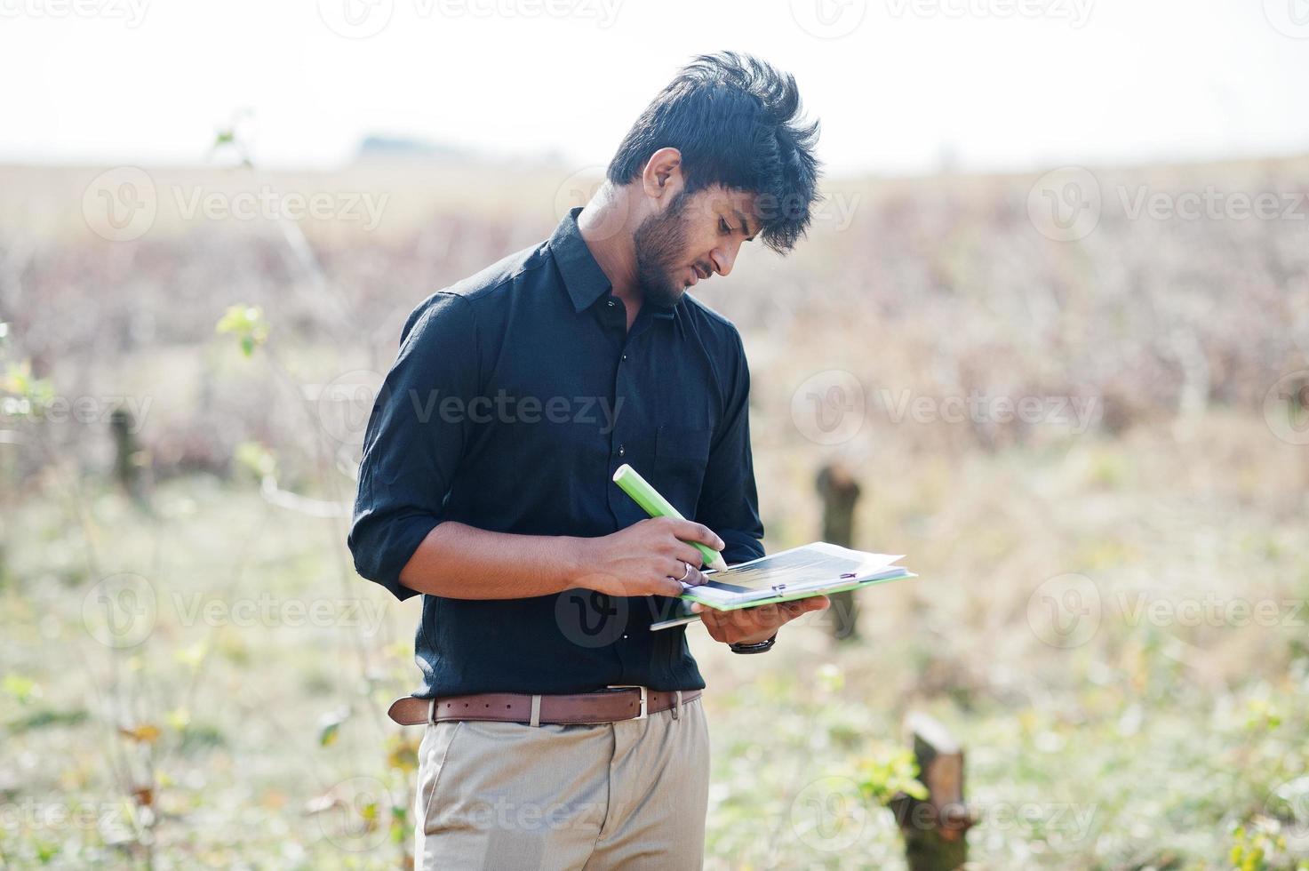 South asian agronomist farmer with clipboard inspecting cut trees in the farm garden. Agriculture production concept. photo