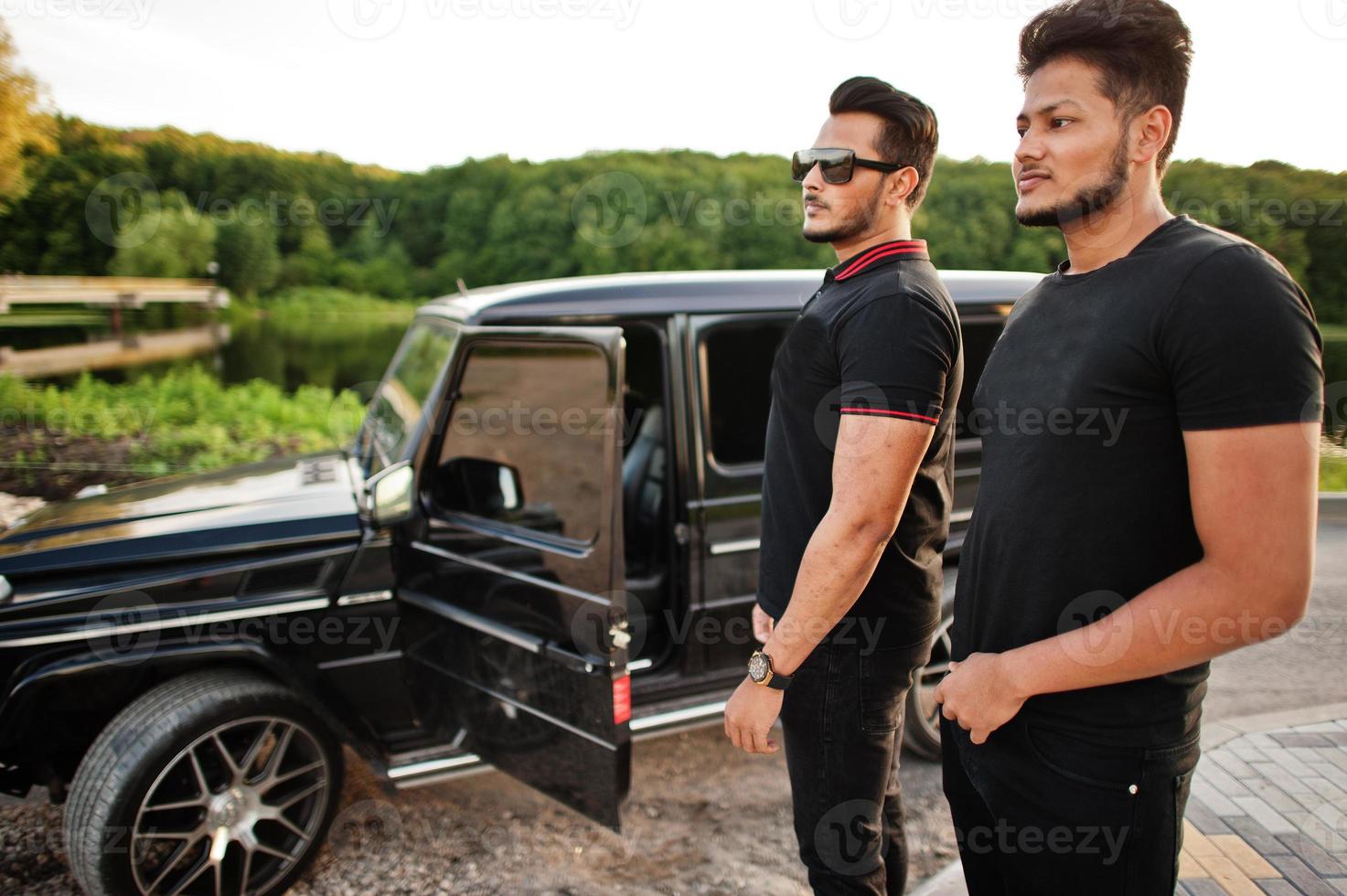 Two asian brothers man wear on all black posed near suv car. photo