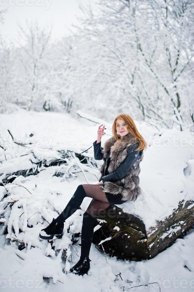 Red haired girl walking at park with husky dog on winter day. photo