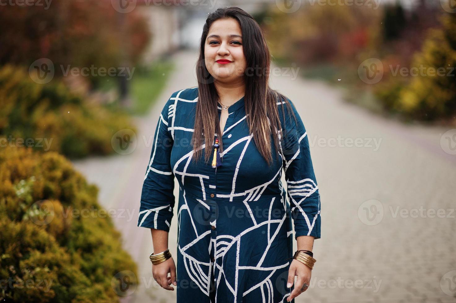 Brunette indian woman in long fashionable dress posed outdoor. photo