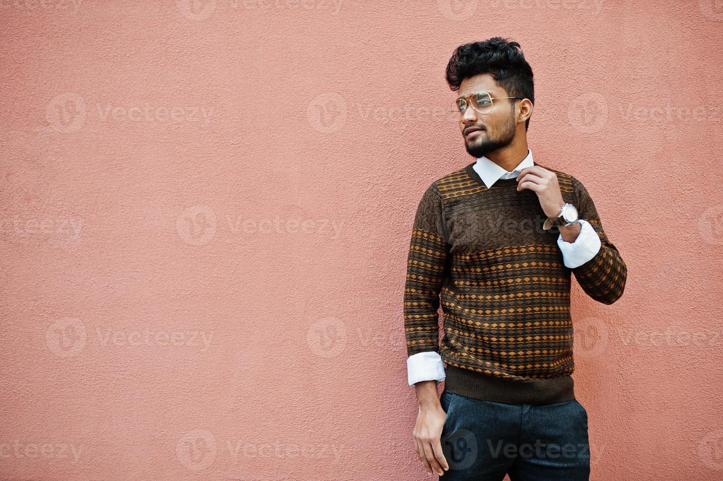 Portrait of young stylish indian man model in eyeglasses isolated on pink wall background. photo