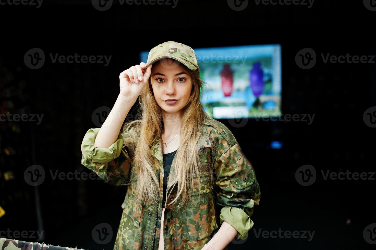 Military girl in camouflage uniform against army background on shooting range. photo
