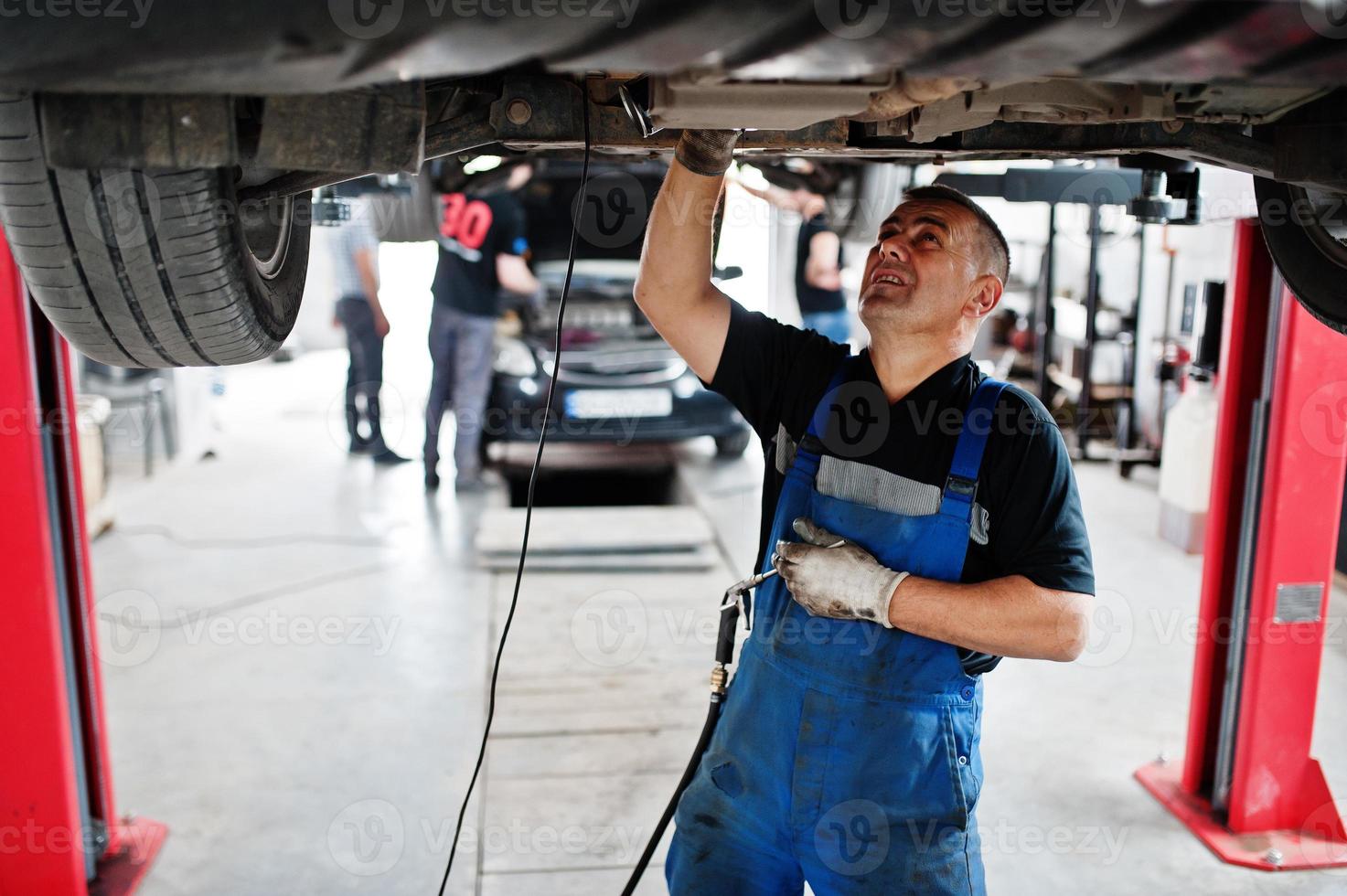 Car repair and maintenance theme. Mechanic in uniform working in auto service. photo