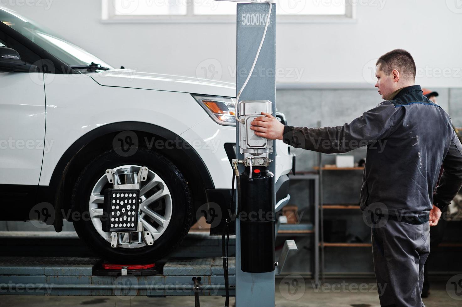 Auto mechanic sets american SUV car for diagnostics and configuration camber check in workshop of service station.. photo