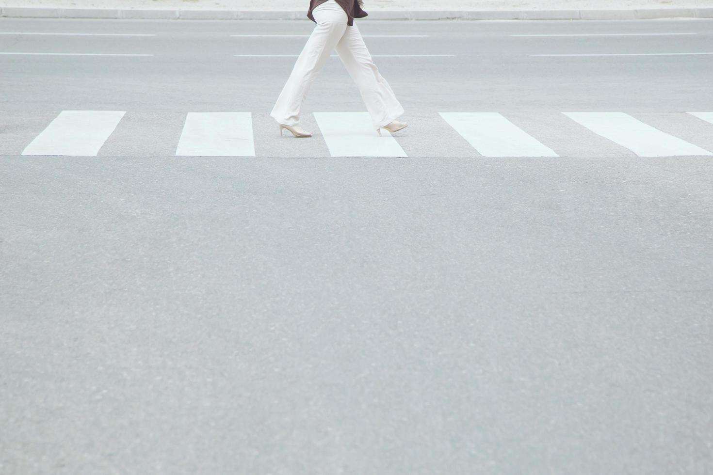 Tourist woman is walking with backpack across the crosswalk at the junction street of city, Pedestrian safety concept,  Leave space empty, write a message on the road. photo