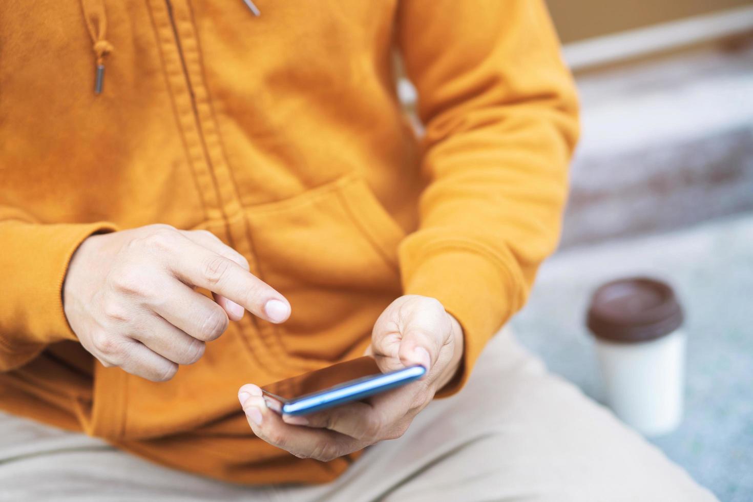 man using phone while sitting on sofa at his modern home.Concept of young people working mobile devices.Blurred background photo