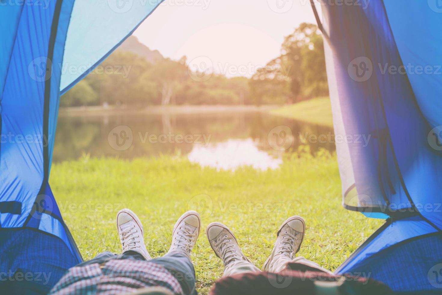 A camping tent glows inside man and woman sleep relaxing inside and watching at the Mountain with river forest. Autumn weekend Outdoor Camping adventure. Freedom travel backpack hiking relax concept. photo