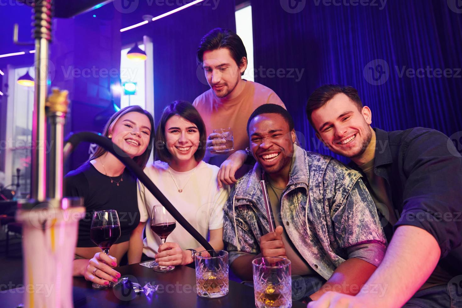 Smiling and partying. Group of friends having fun in the night club together photo