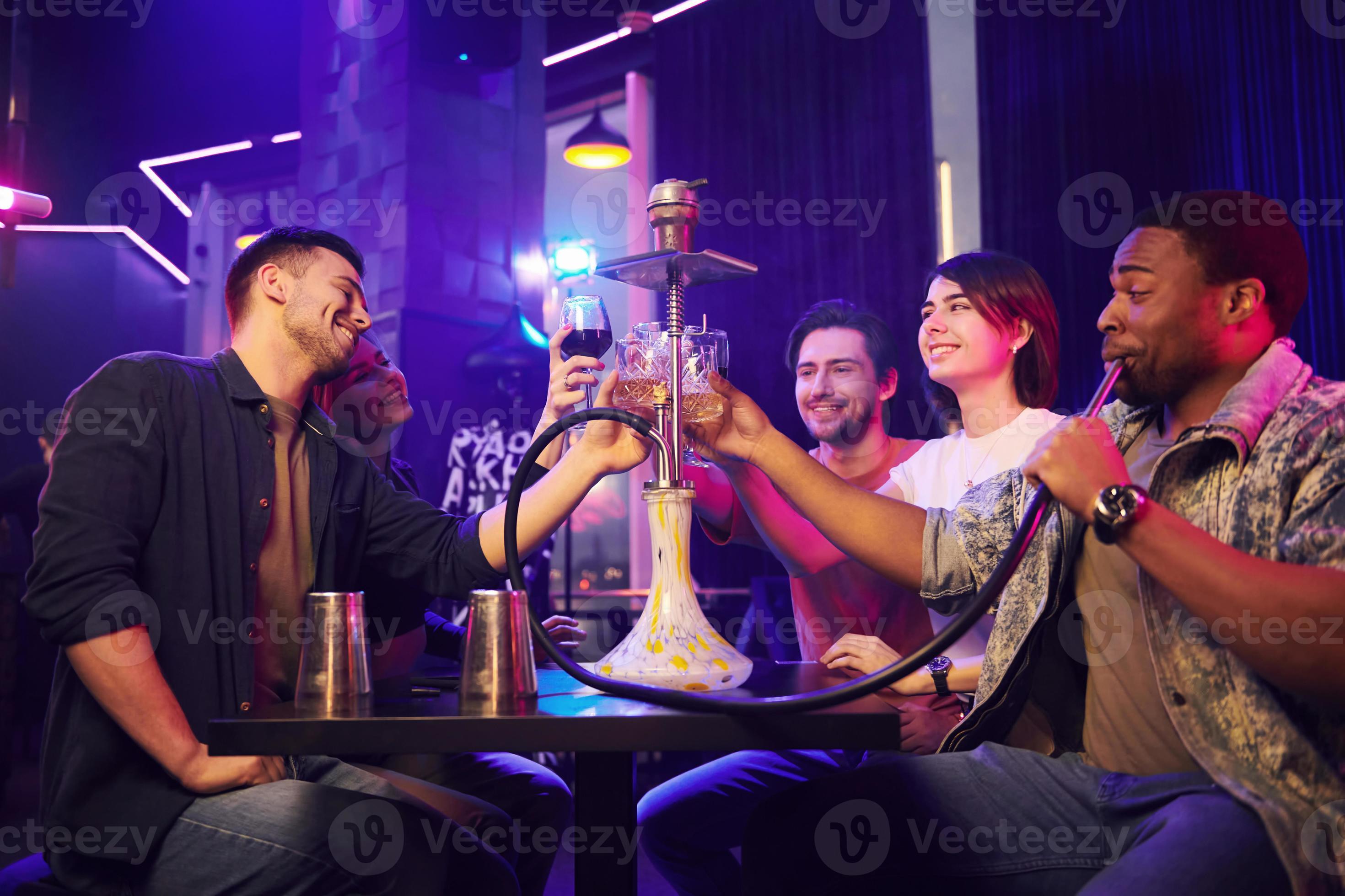 Smoking hookah. Group of friends having fun in the night club together