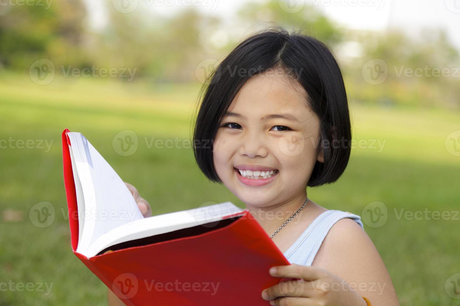 Asian little girl reading book in the park photo