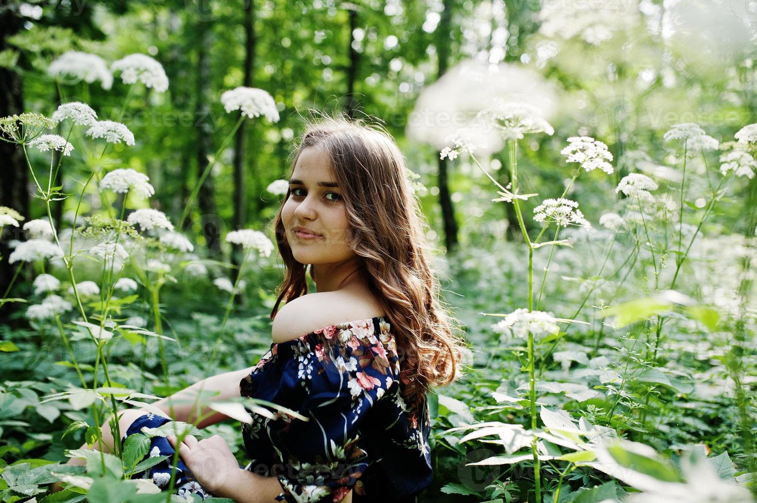 retrato de una joven fabulosa con un bonito vestido con un elegante peinado rizado posando en el bosque o en el parque. foto