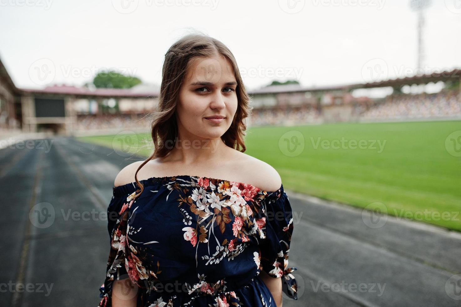 Portrait of a fabulous girl in dress and high heels on the track at the stadium. photo