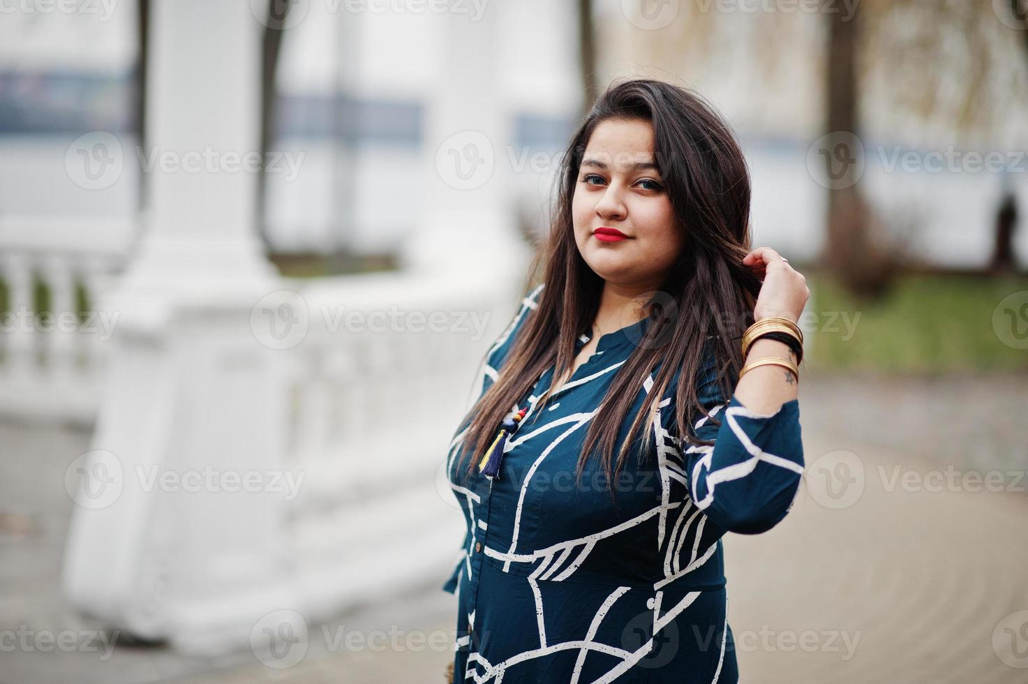 Brunette indian woman in long fashionable dress posed outdoor. photo