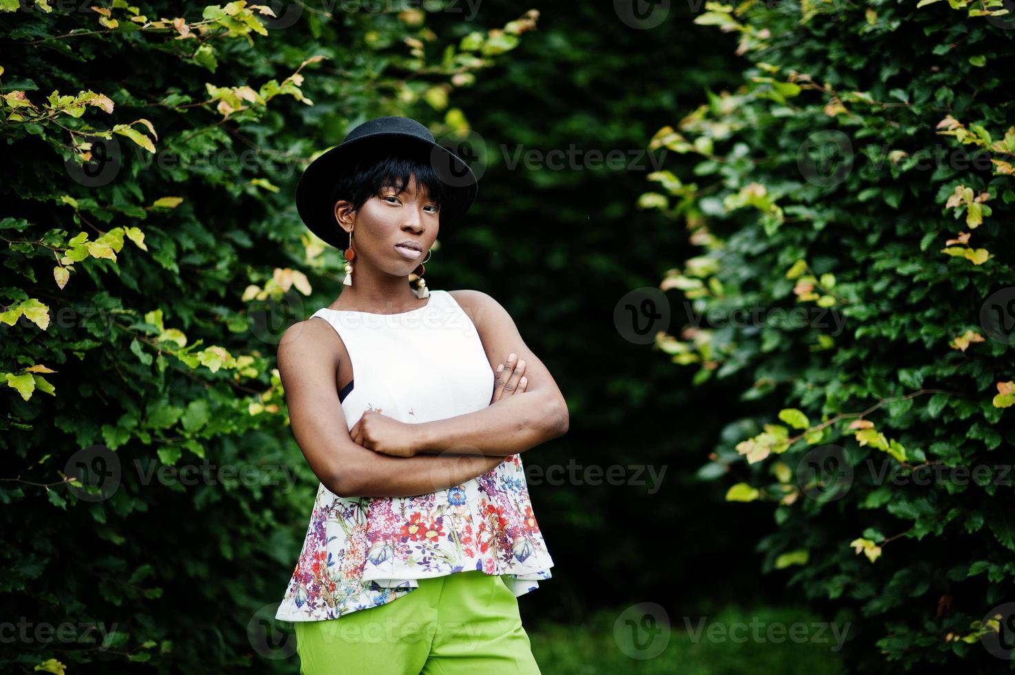 increíble mujer modelo afroamericana en pantalones verdes y sombrero negro posó en el parque. foto