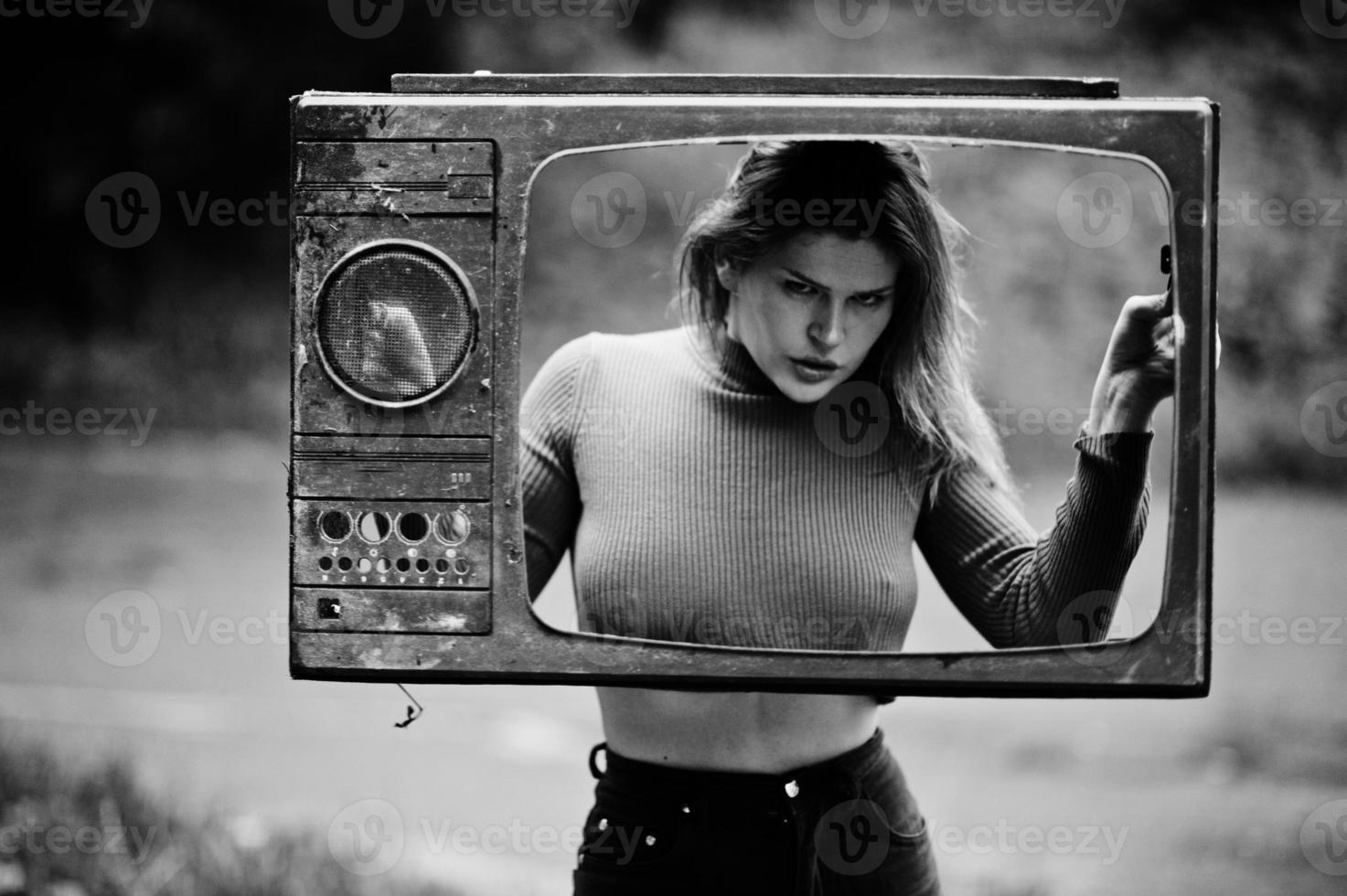 Fashion portrait of redhaired sexy girl outdoor. Model attractive dramatic woman with old tv box. photo