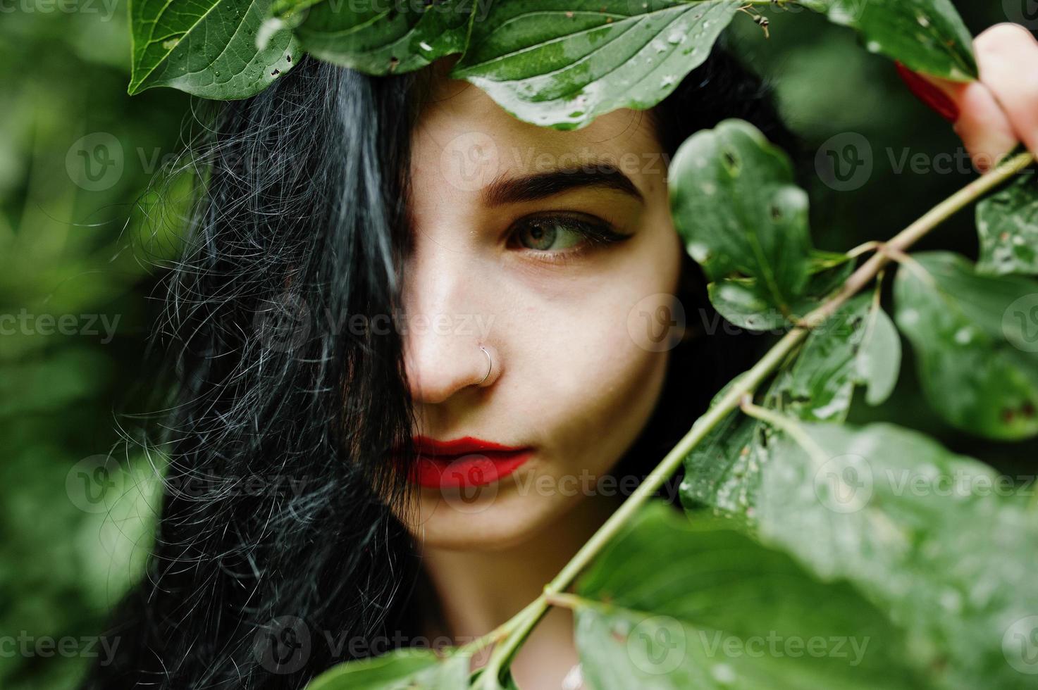 Close up portrait of sensual brunette girl with red lips. Goth dramatic woman at tree branch. photo