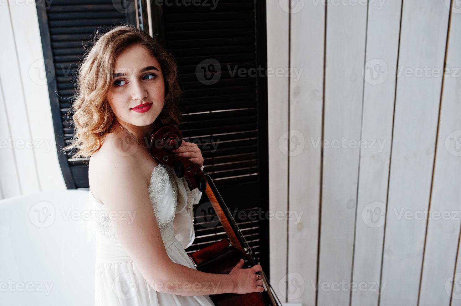 Pretty young gilrl musician in white dress with double bass. photo