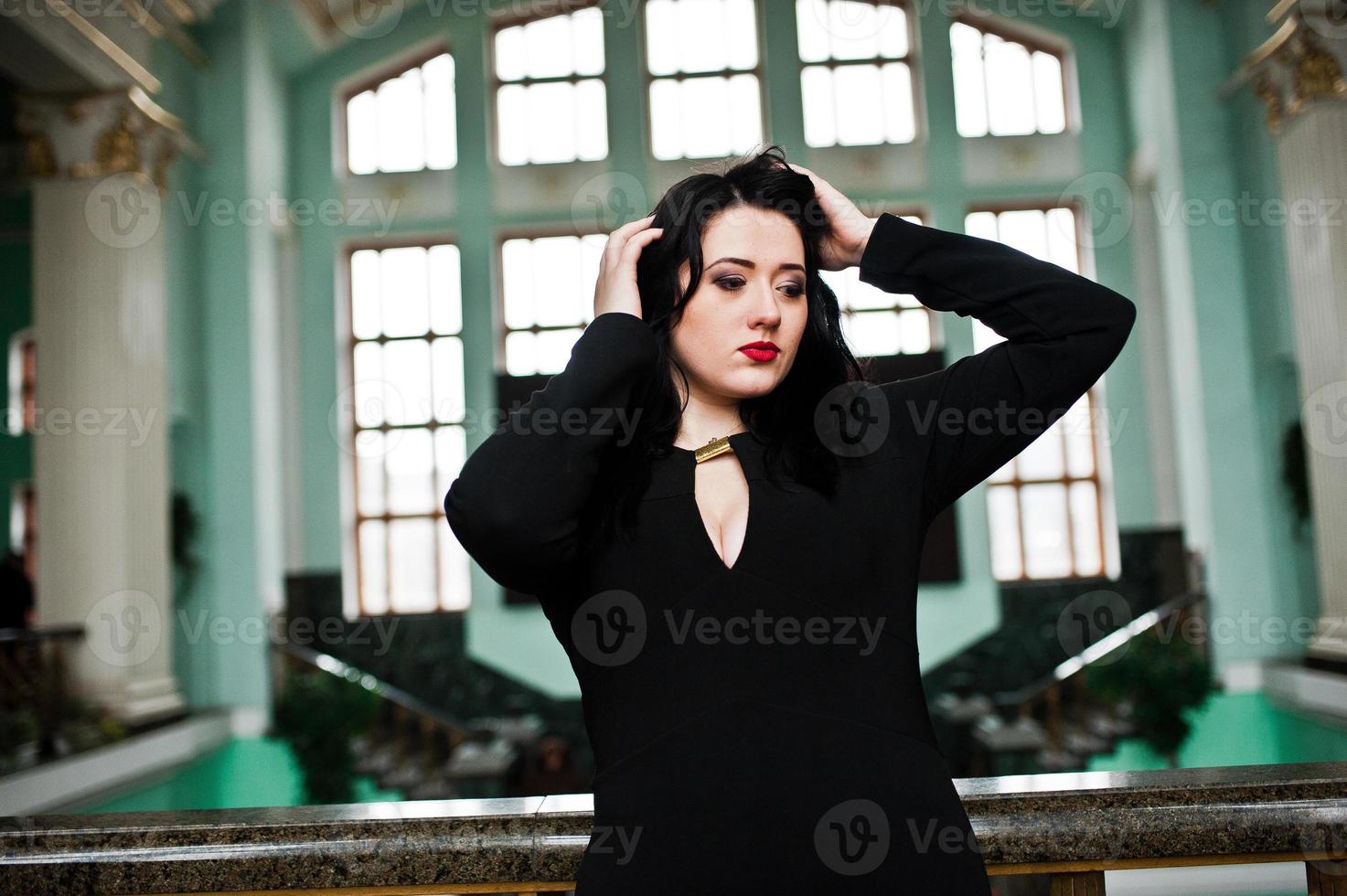 chica morena con vestido negro en la estación de tren interior. foto