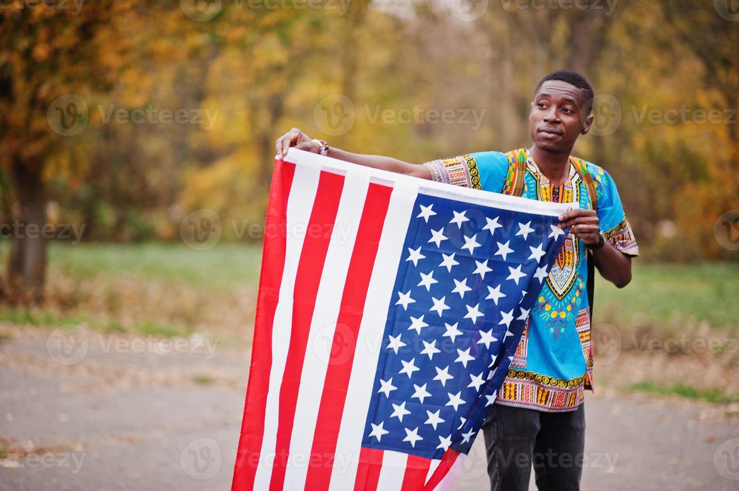 African man in africa traditional shirt on autumn park with USA flag. photo