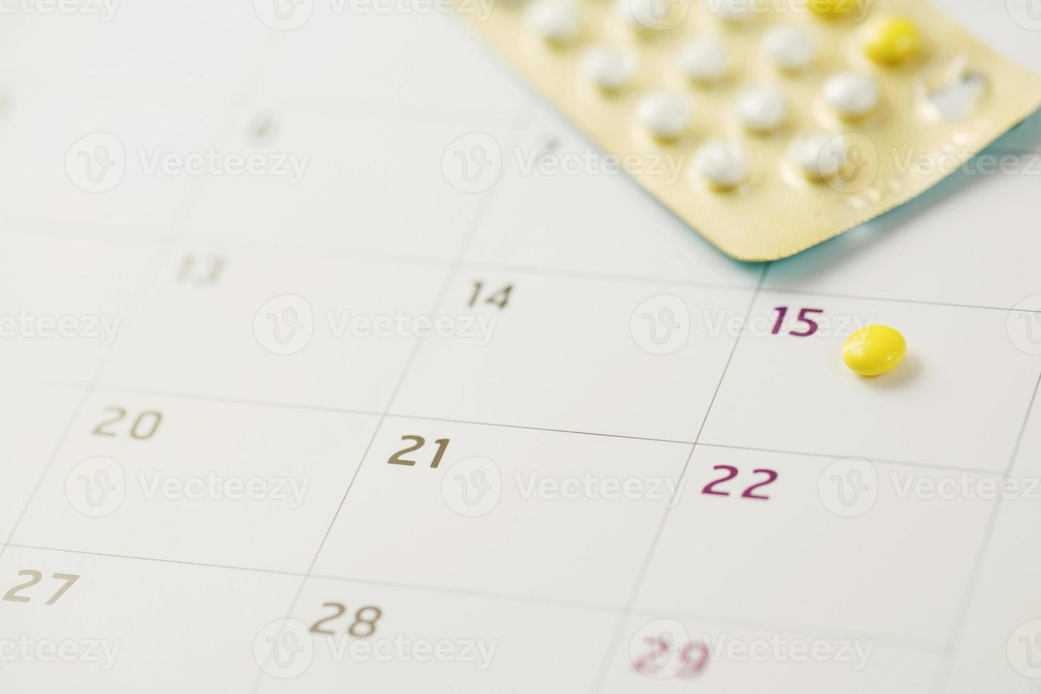 píldoras anticonceptivas en la fecha de fondo del calendario. concepto de control de la natalidad de atención médica y medicamentos. foto