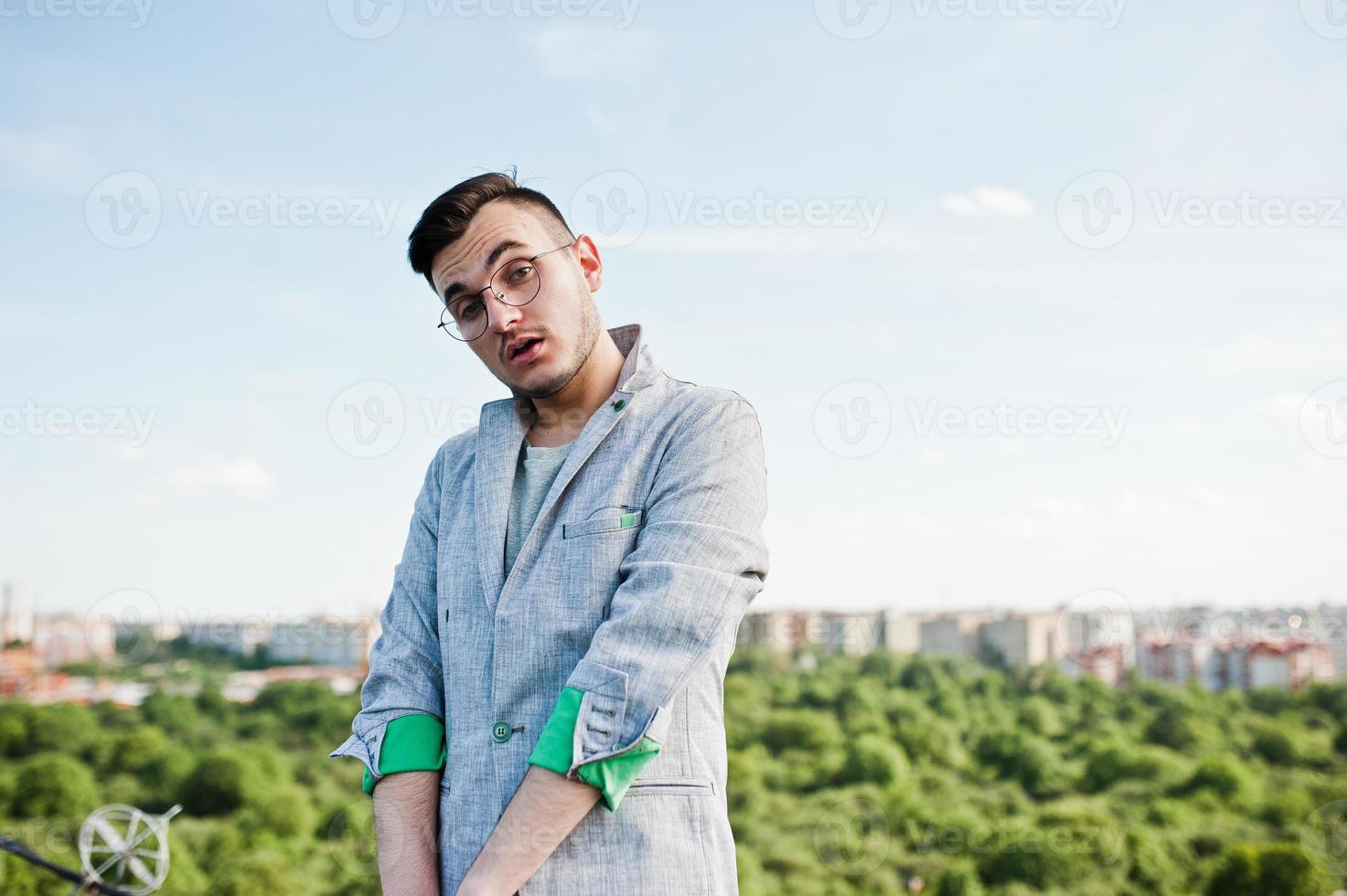 hombre macho con estilo soñador en traje gris y gafas posadas en el techo. foto