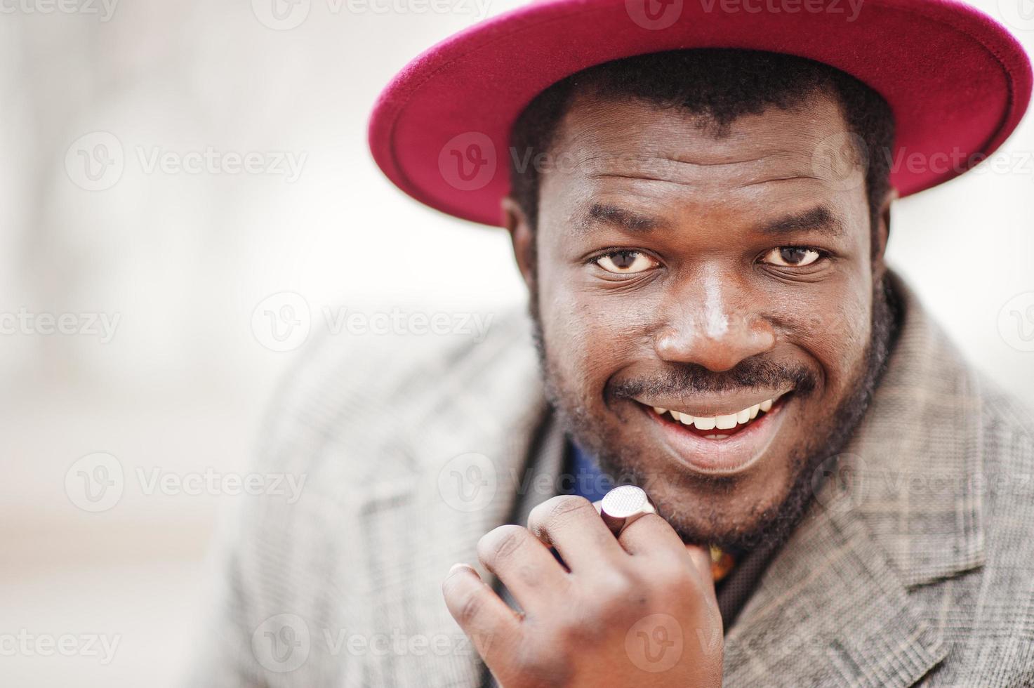 Close up portrait of stylish African American man model in gray coat, jacket tie and red hat. photo