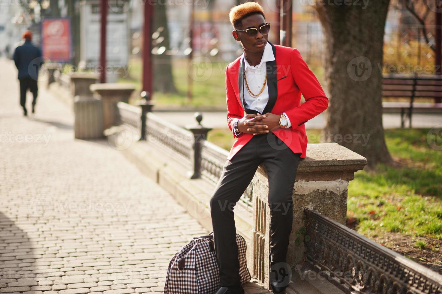 Fashion african american man model at red suit, with highlights hair and handbag posed at street. photo