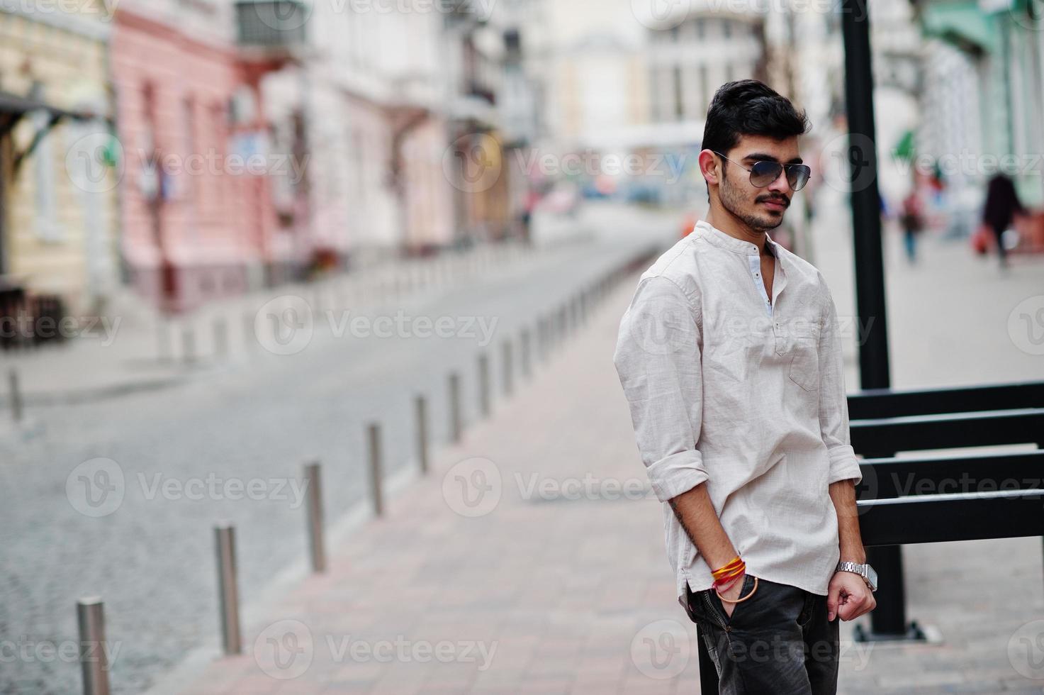 Stylish indian model man in casual clothes and sunglasses posed outdoor at street of India. photo