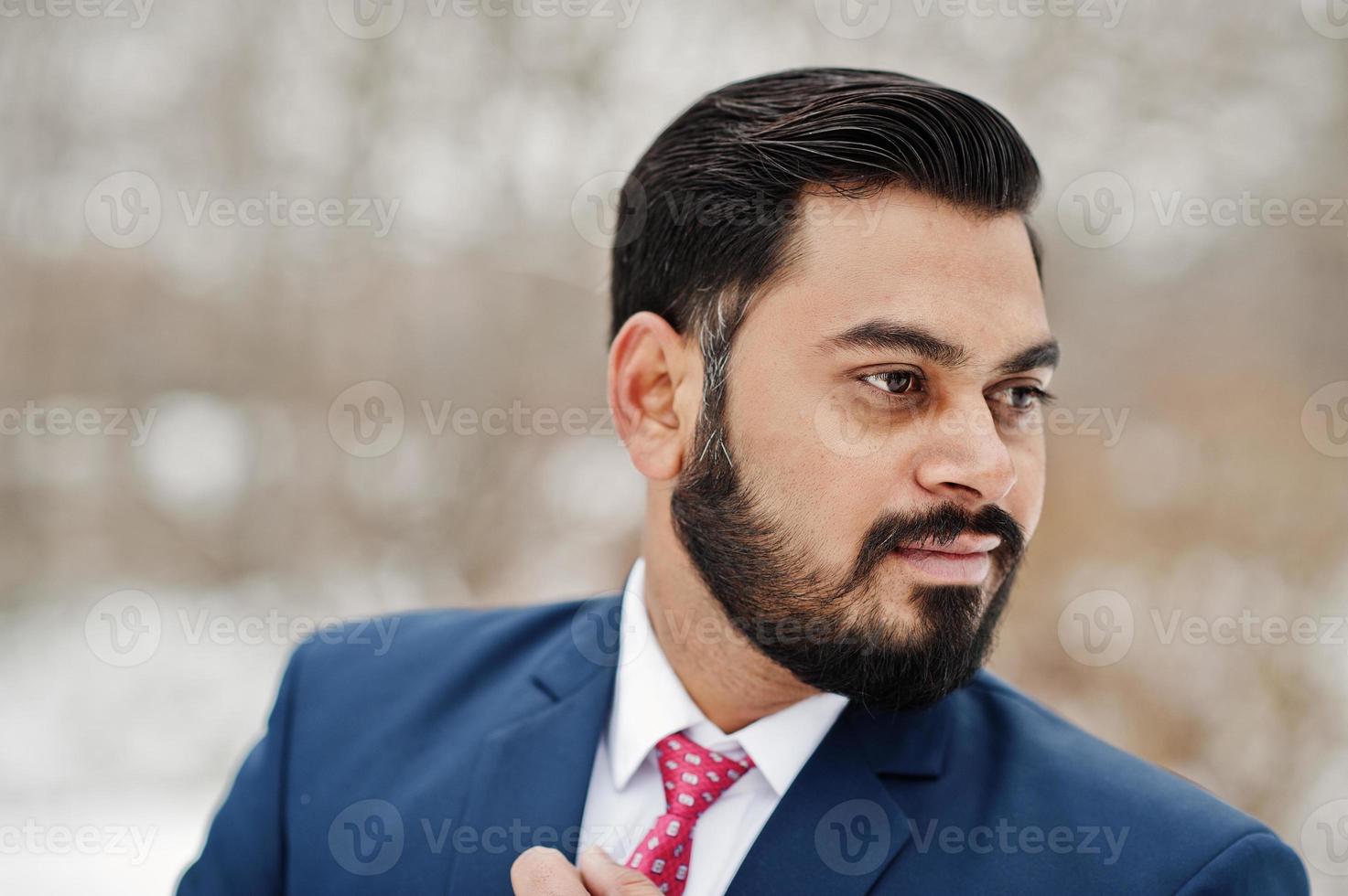 primer plano retrato de elegante hombre de negocios de barba india en traje posado en el día de invierno al aire libre. foto