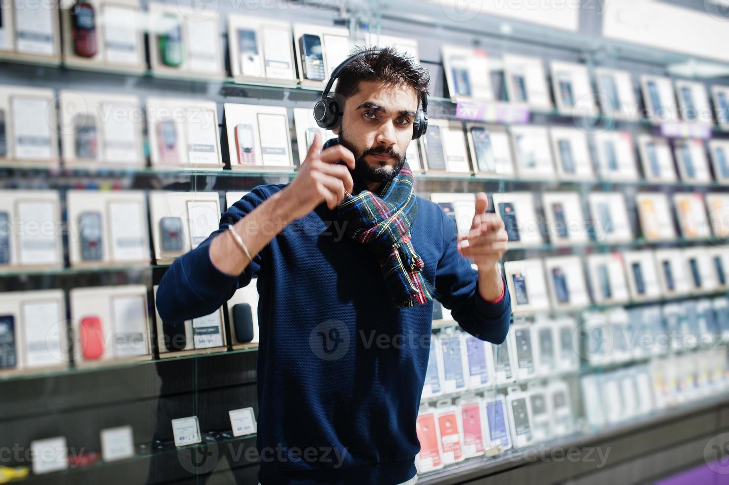 Indian beard man customer buyer at mobile phone store with wireless earphones. South asian peoples and technologies concept. Cellphone shop. photo