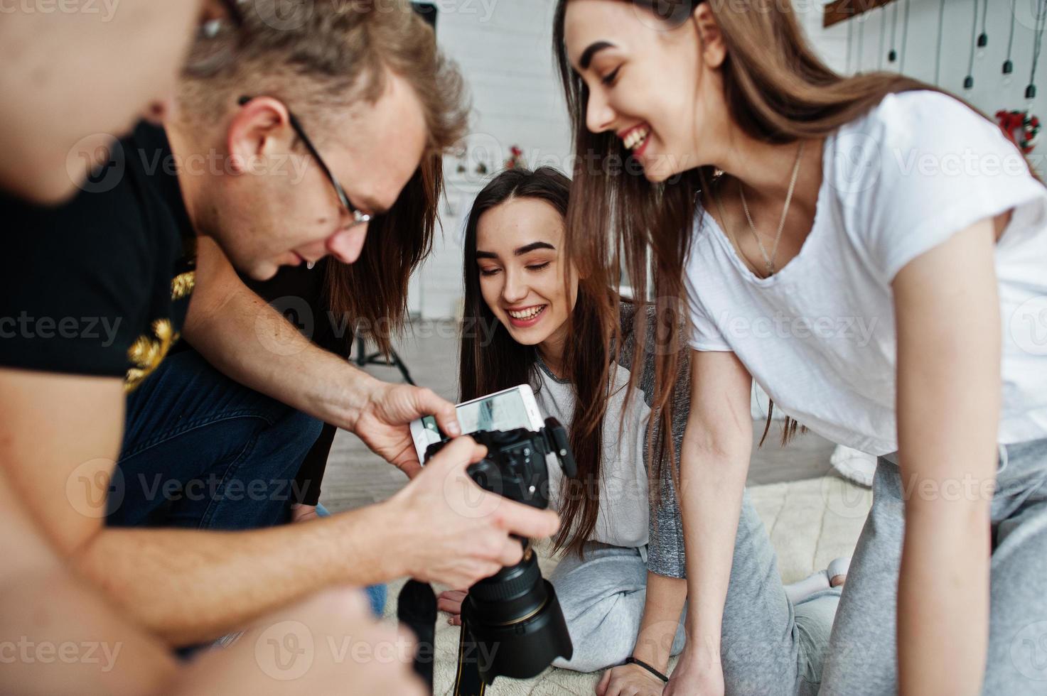The team of photographers showing pictures on screen of camera for twins models girls on studio. Professional photographer on work. photo