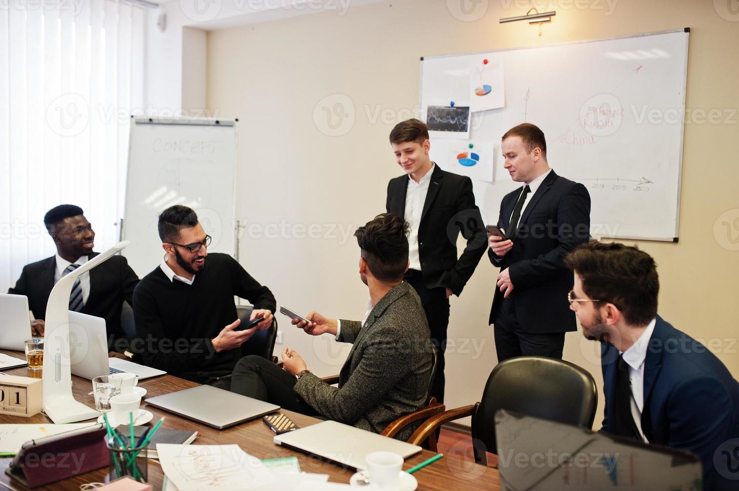 Six multiracial business mans at office at table. Diverse group of male employees in formal wear discussing. photo