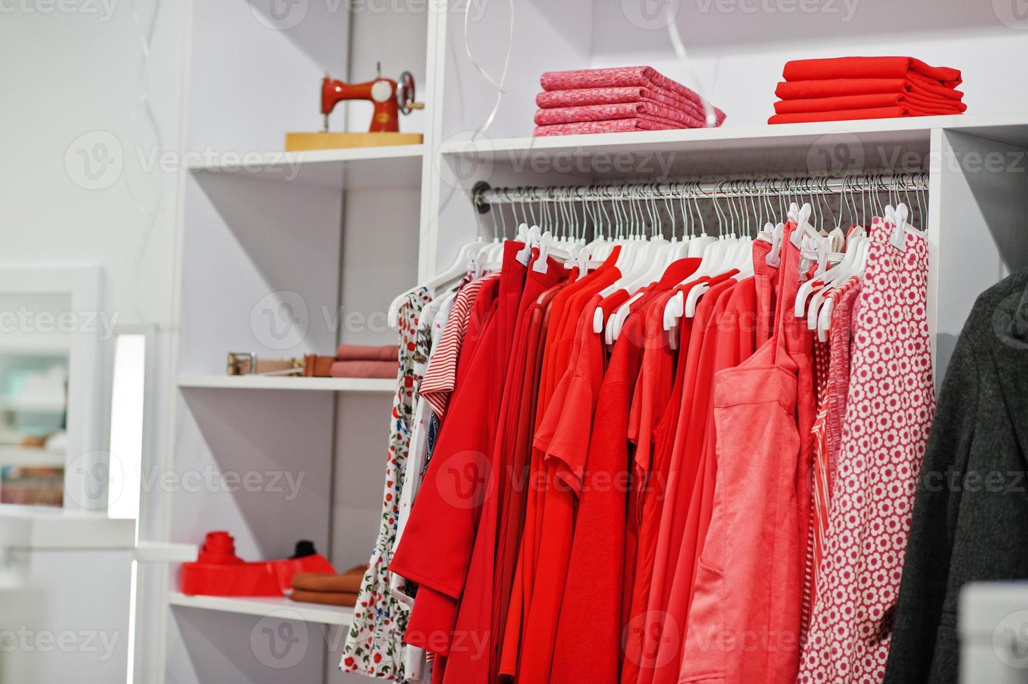 conjunto de ropa de color rojo femenino en los bastidores y estantes en la tienda de ropa nueva boutique moderna. colecciones de vestidos primavera verano. foto