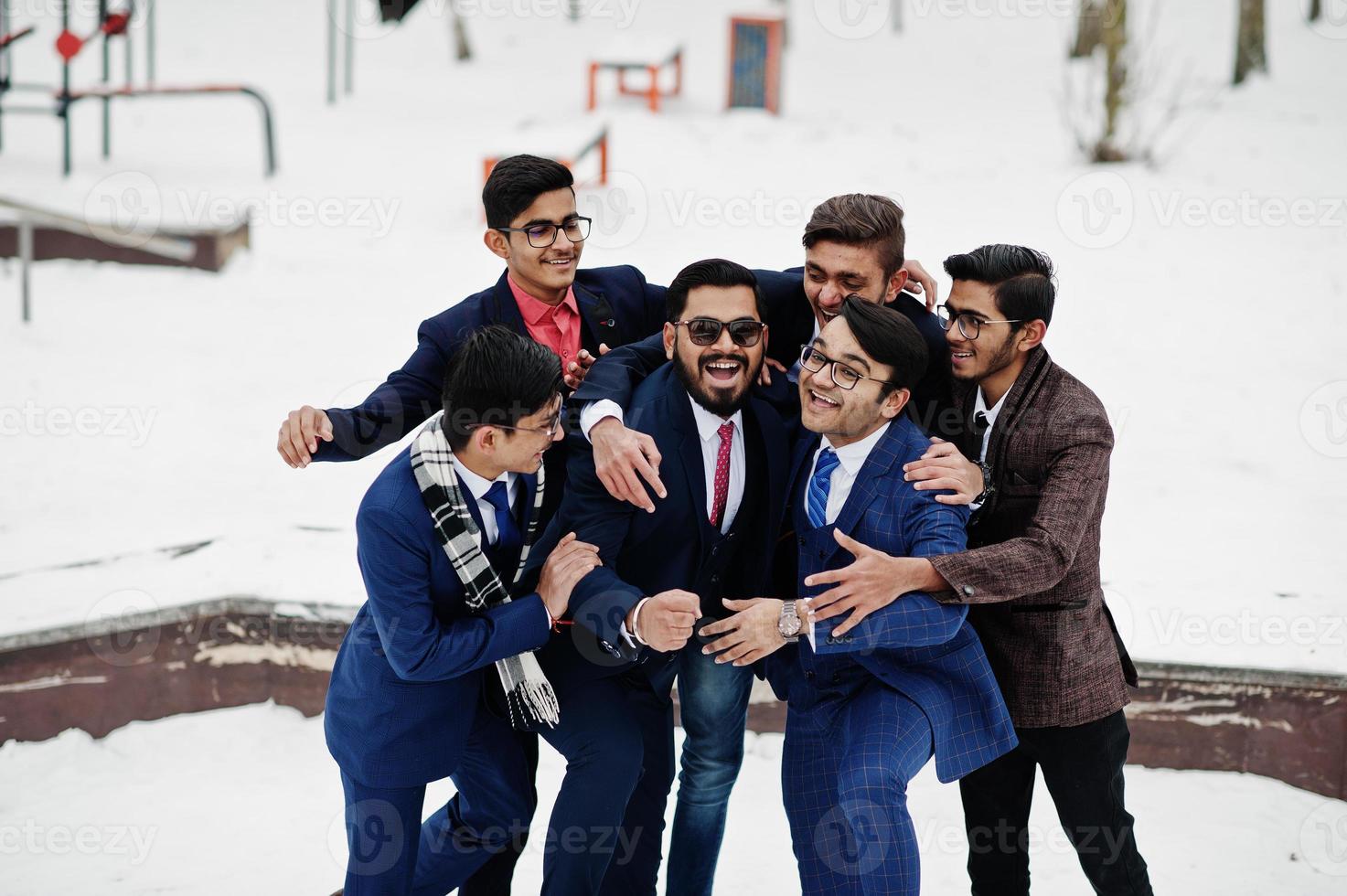 Group of six indian businessman in suits posed outdoor in winter day at Europe, hugs and happy emotions. photo