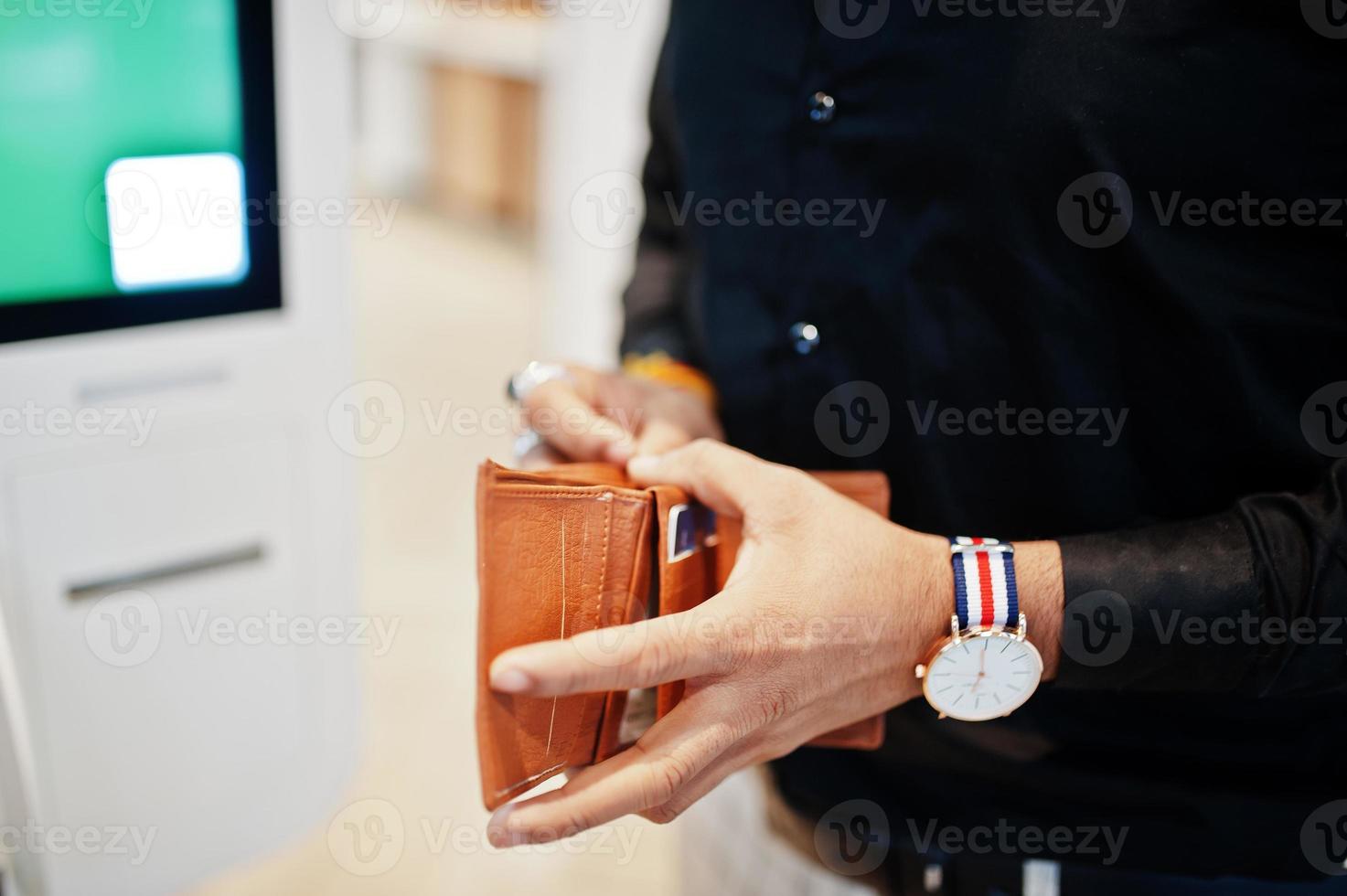 Hands of man customer at store place orders and pay through self pay floor kiosk for fast food, payment terminal. His holding wallet and find credit card. photo