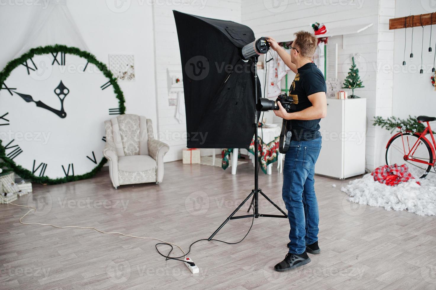 Photographer adjusts the flash light on studio. photo