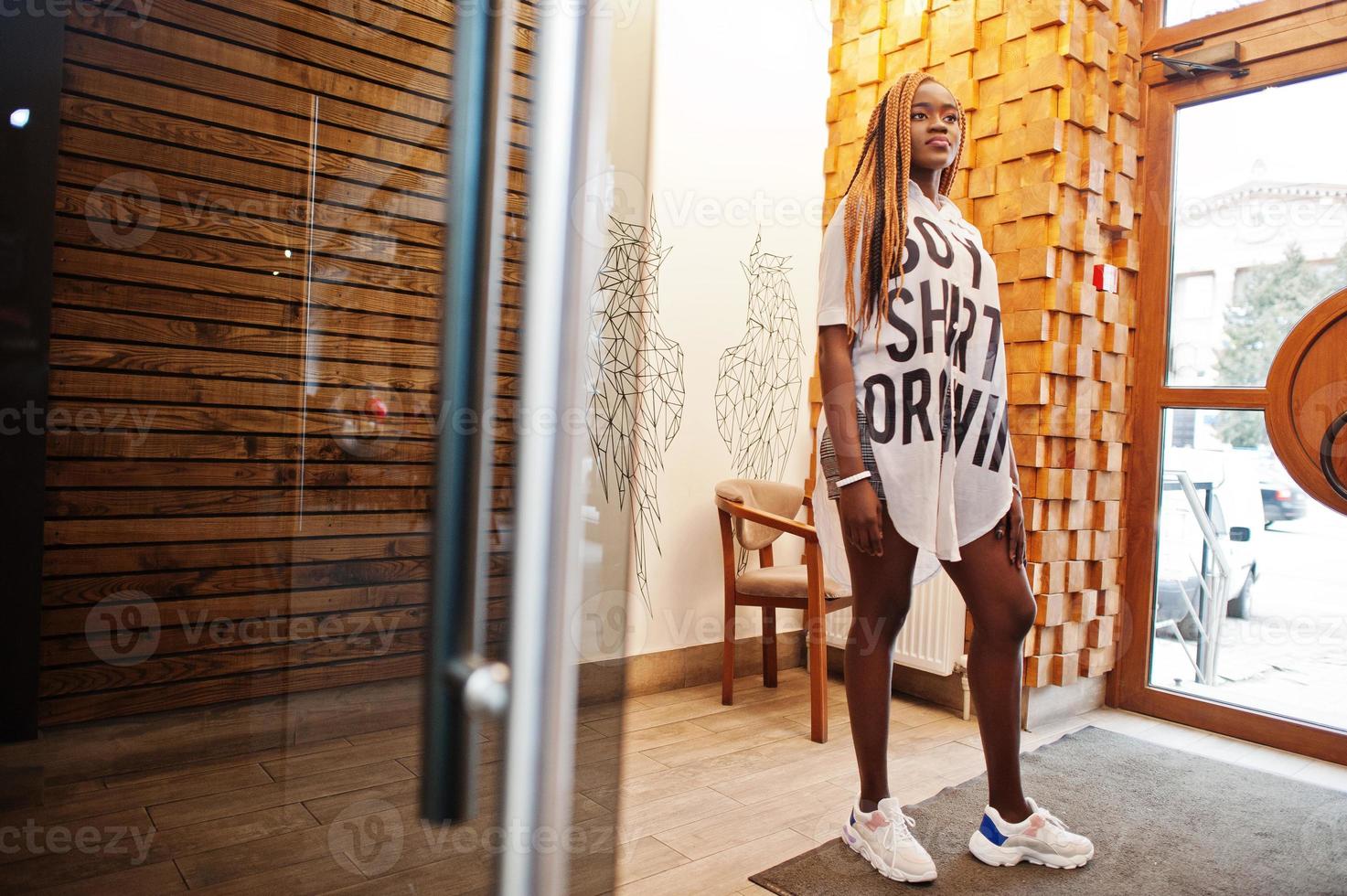 Beautiful african woman in stylish casual clothes posing against angel wings wall. photo