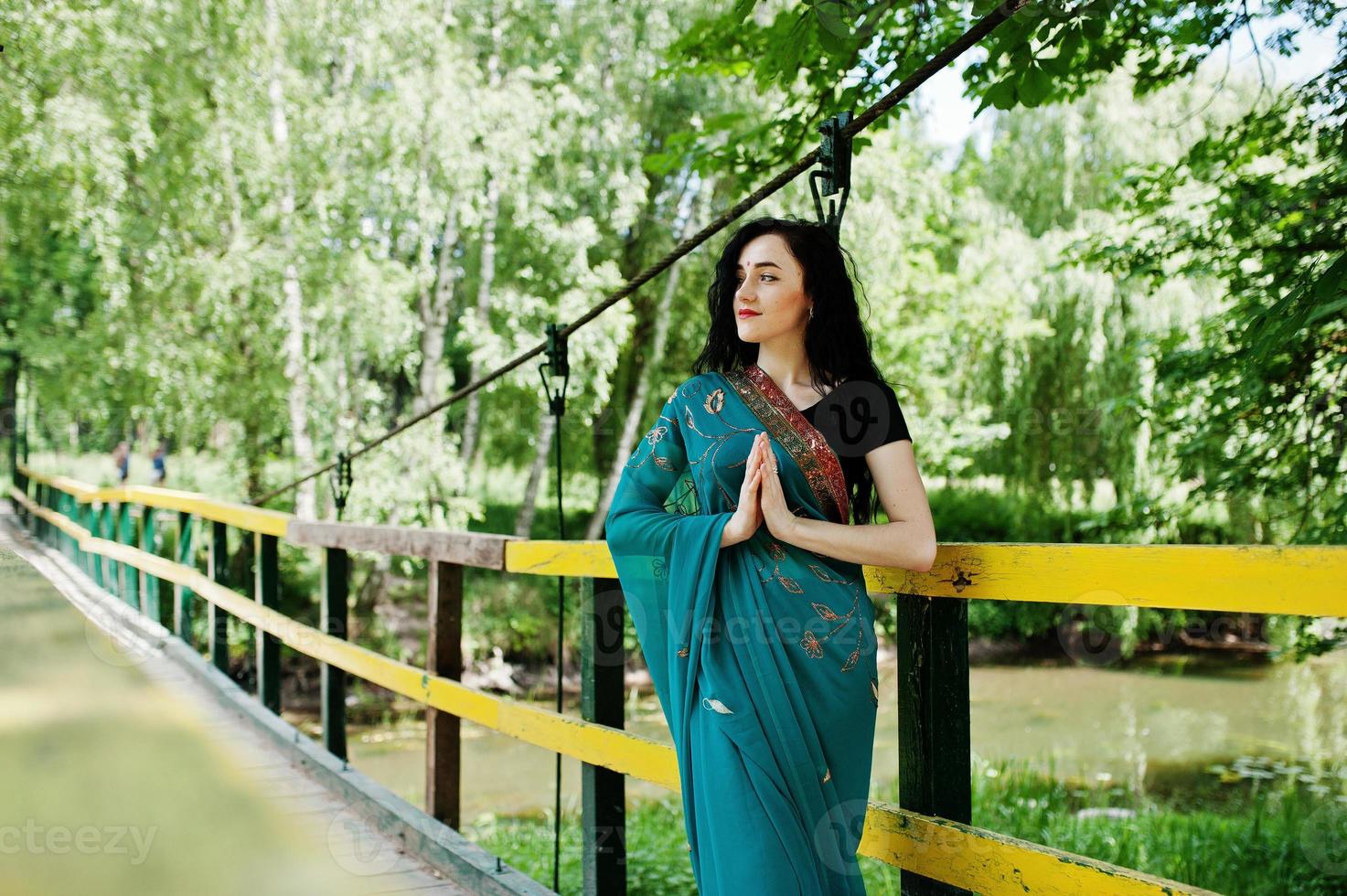 Portrait of beautiful indian brumette girl or hindu woman model on bridge. Traditional Indian costume lehenga choli. photo