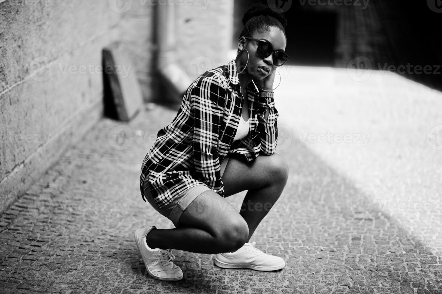 Hip hop african american girl on sunglasses and jeans shorts. Casual street fashion portrait of black woman. photo