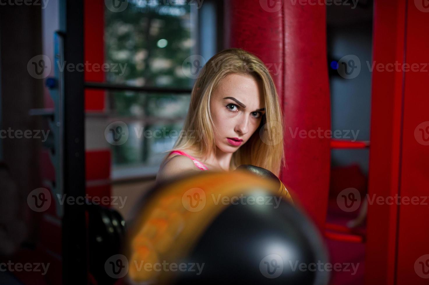 Sexy sport blonde girl punching bag. Fit woman boxing. photo