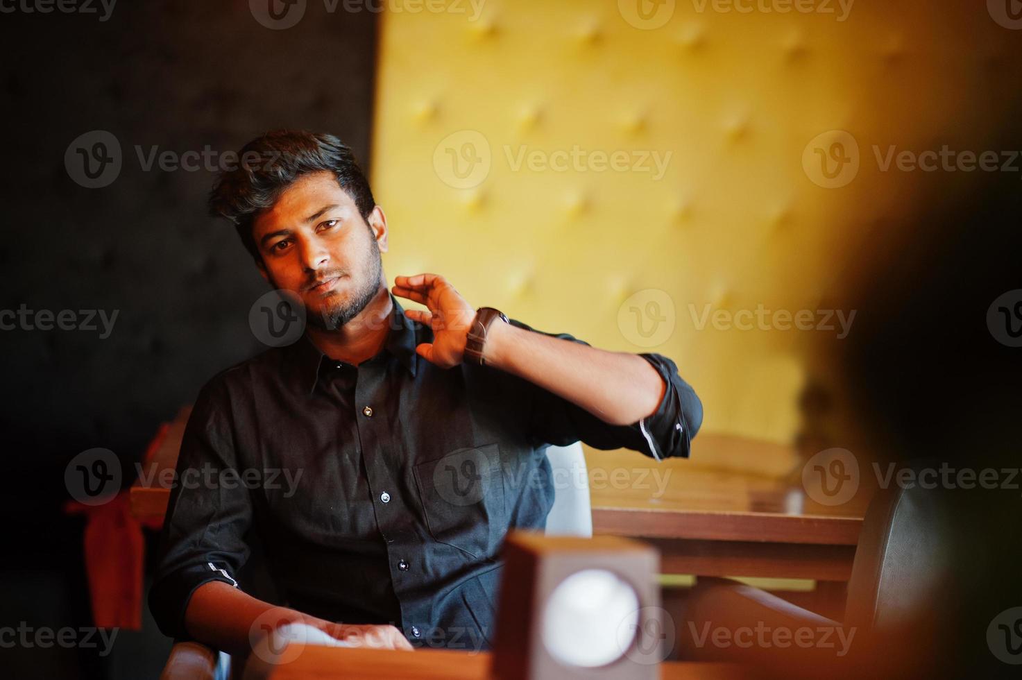 Confident young indian man in black shirt sitting at cafe. photo