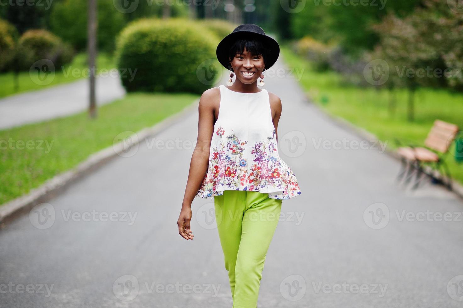 Increíble mujer modelo afroamericana con pantalones verdes y sombrero negro posó con diferentes emociones en el parque. foto