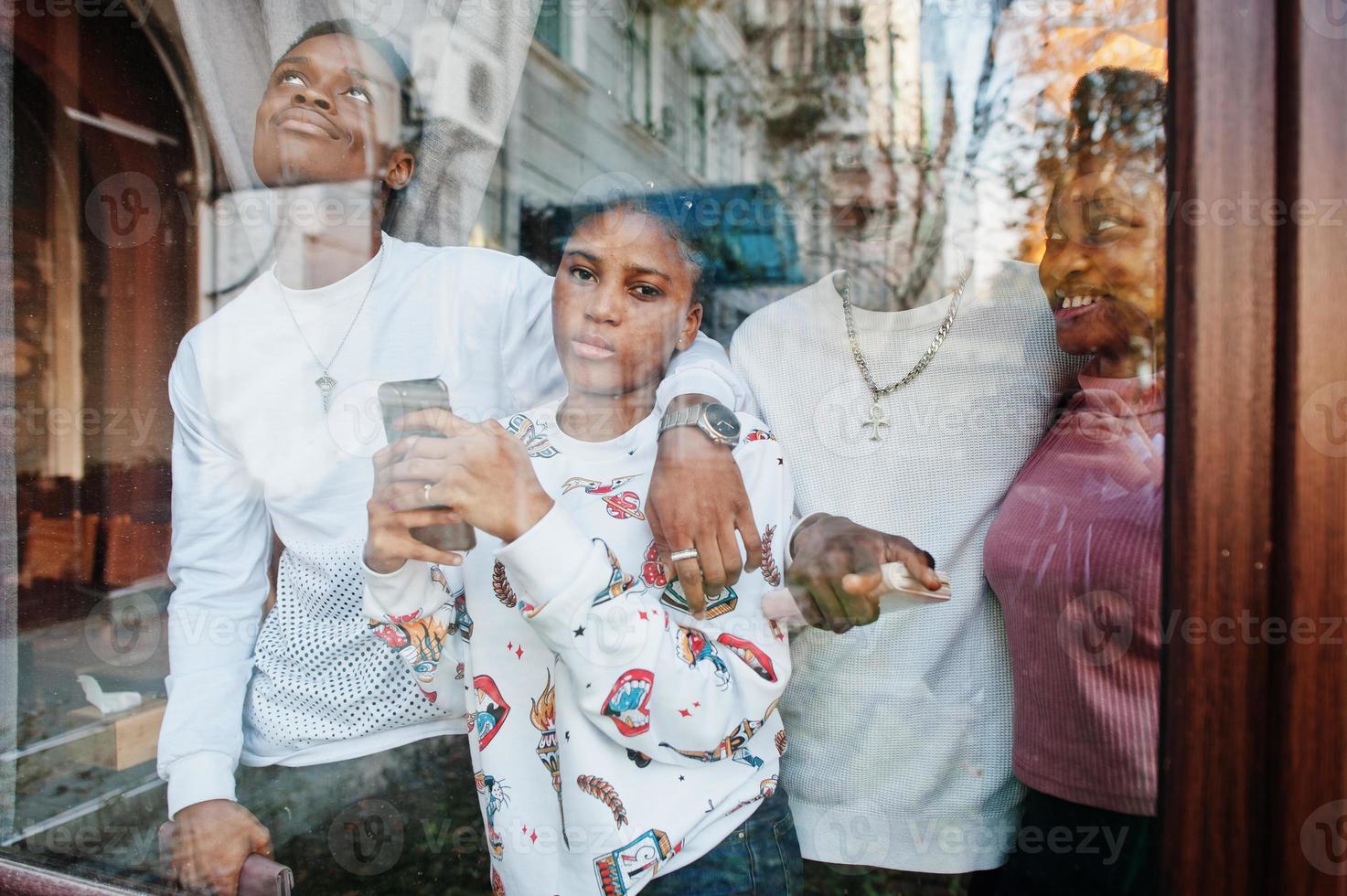 amigos africanos felices charlando en el café. grupo de personas negras reunidas en un restaurante contra el cristal de la ventana. foto