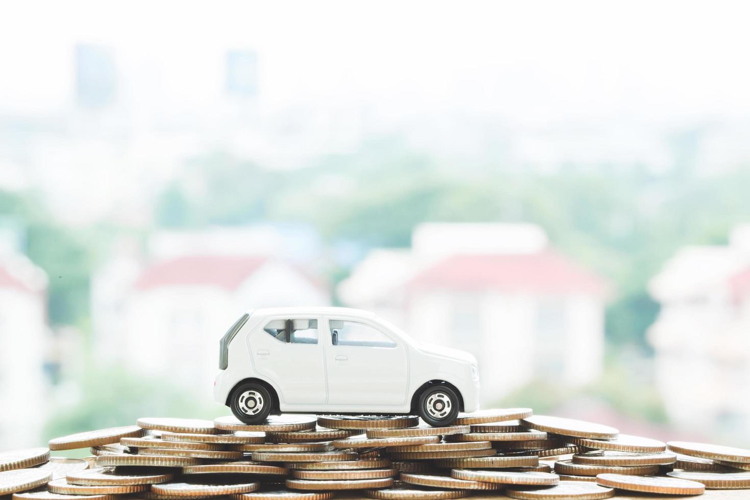 pequeño coche sobre un montón de monedas apiladas de dinero con casa de fondo. por concepto de financiación de costos de préstamos. con tonos de filtro efecto retro vintage, tonos cálidos. foto