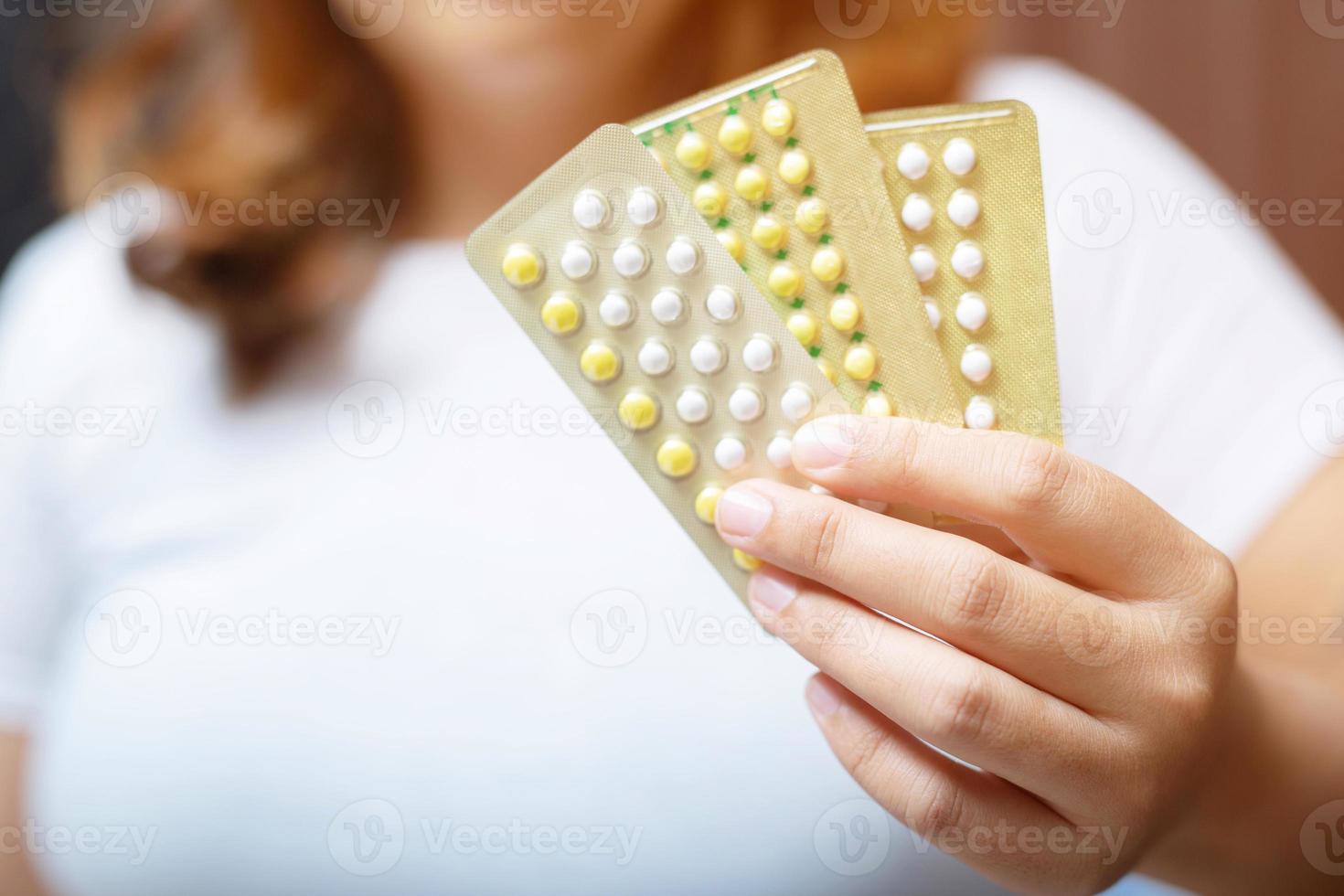 manos de mujer abriendo píldoras anticonceptivas en la mano. comiendo píldora anticonceptiva. foto