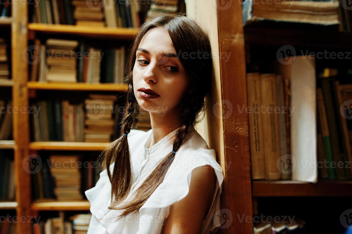 chica con coletas en blusa blanca en la antigua biblioteca. foto