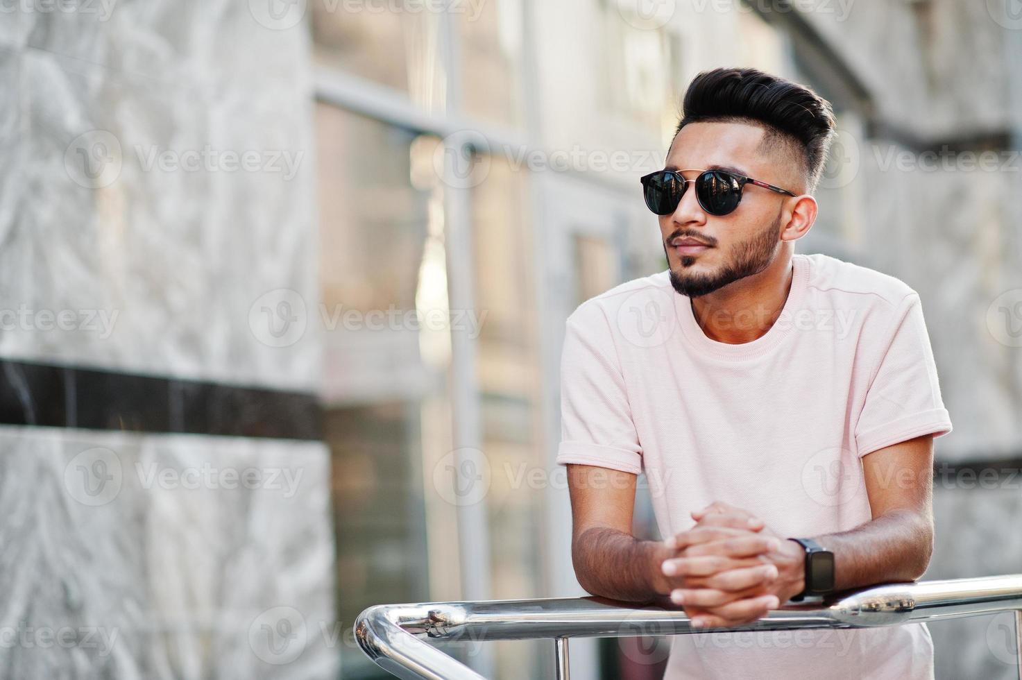 elegante hombre de barba india con gafas de sol y camiseta rosa. modelo india posó al aire libre en las calles de la ciudad. foto