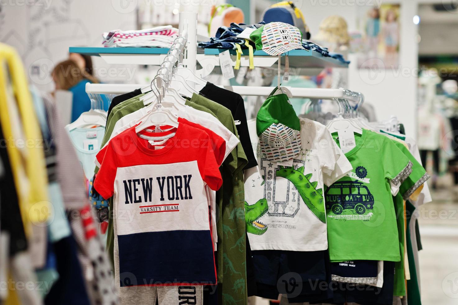 Children's bright clothes hang on the display in the baby clothing store. Boys section. photo